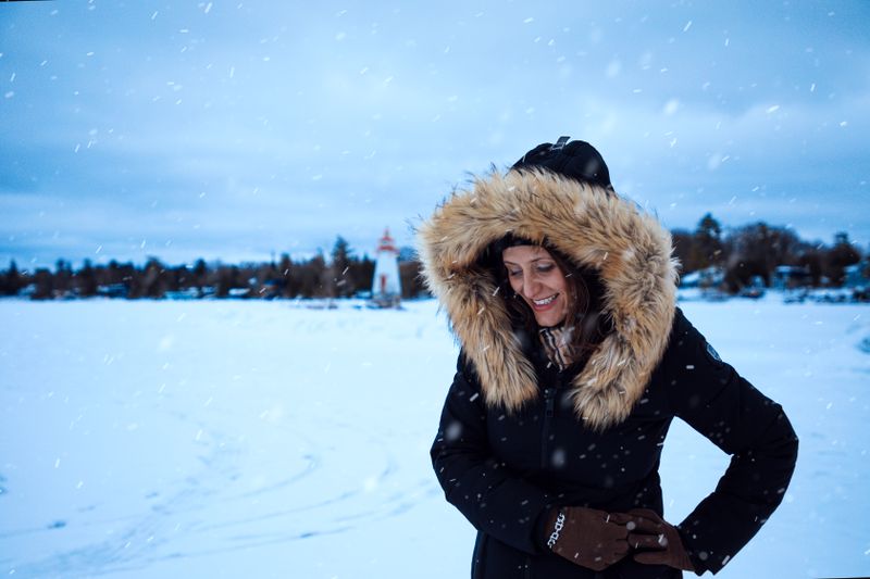 Woman in fur-lined coat smiling on a snowy day