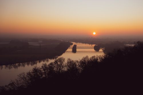 Free Peaceful sunset view over a serene river, reflecting a warm golden glow, creating a tranquil atmosphere. Stock Photo