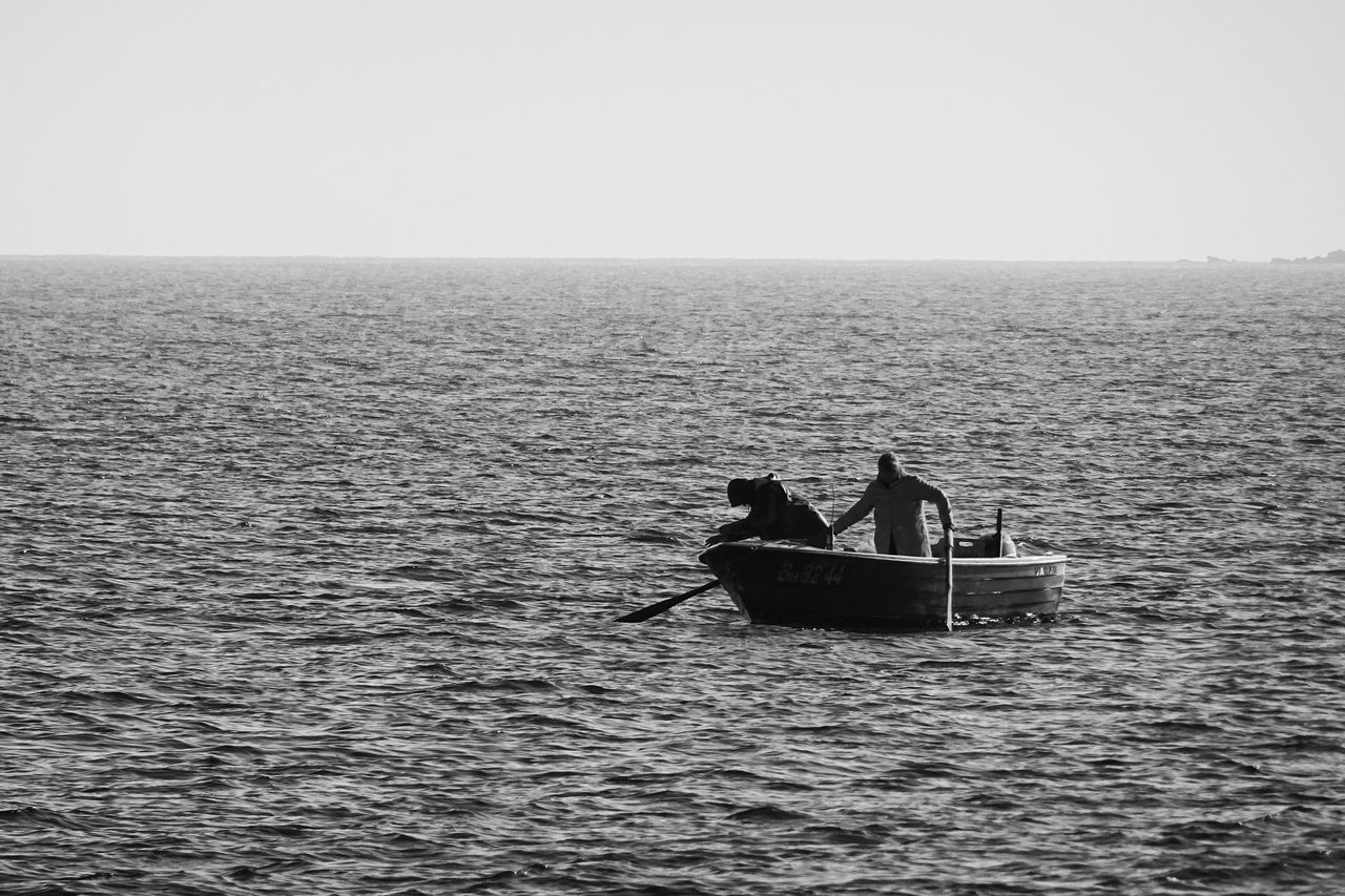 black and white image of a solitary fisherman on a small boat at sea d