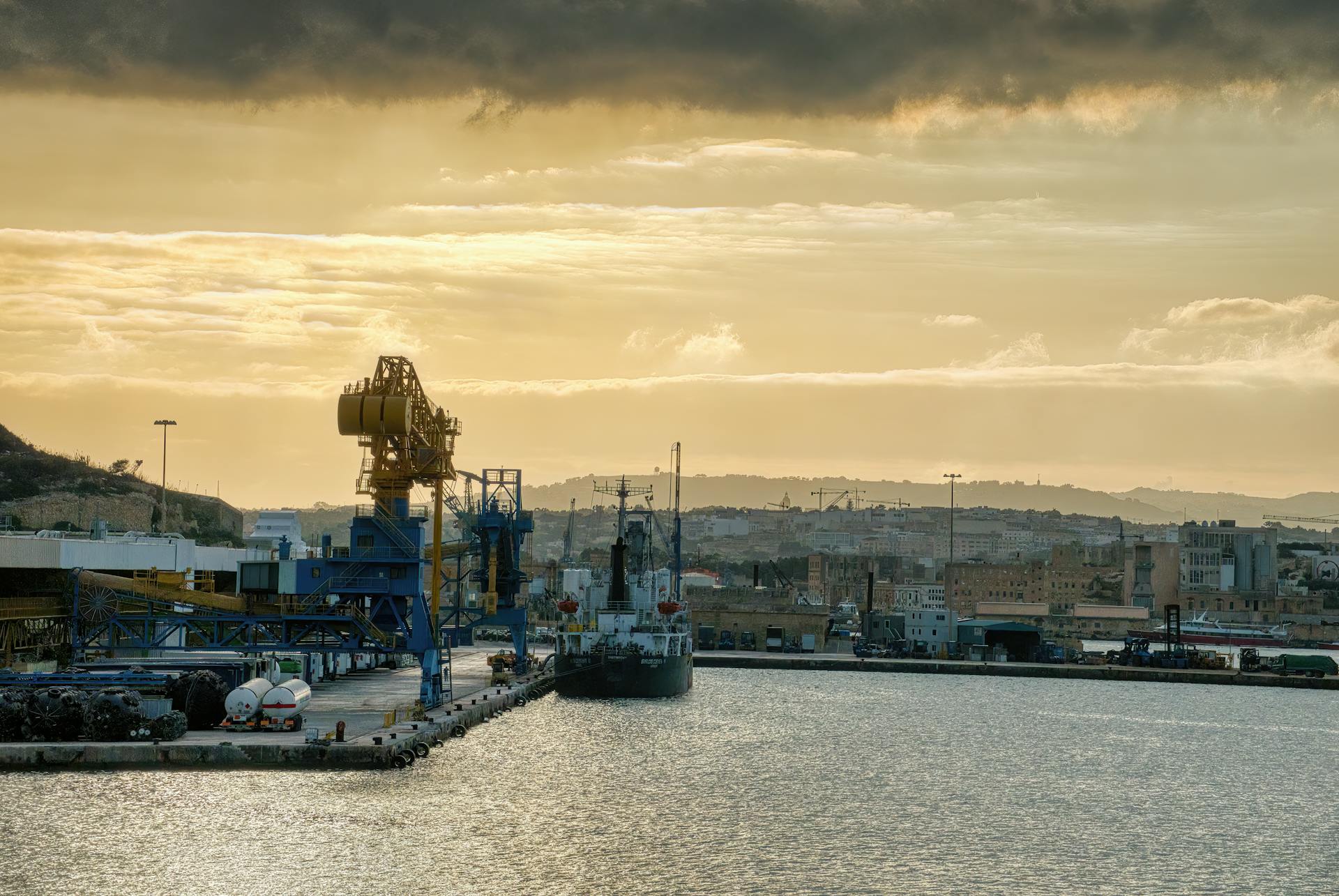 Industrial shipyard in Malta at sunset with cranes and ships showcasing maritime industry.