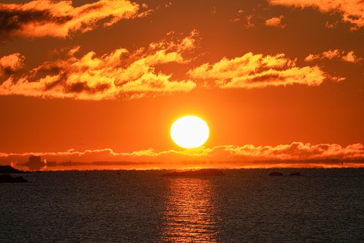 A breathtaking sunrise over the sea with vibrant orange hues reflecting on the water.