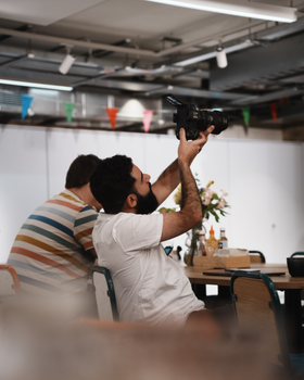 Photographers in casual indoor setting, capturing moments.
