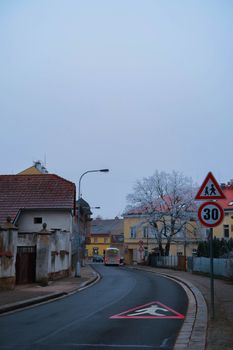 A serene street in Hradec Králové with wintery trees and road signs, displaying a 30 speed limit.