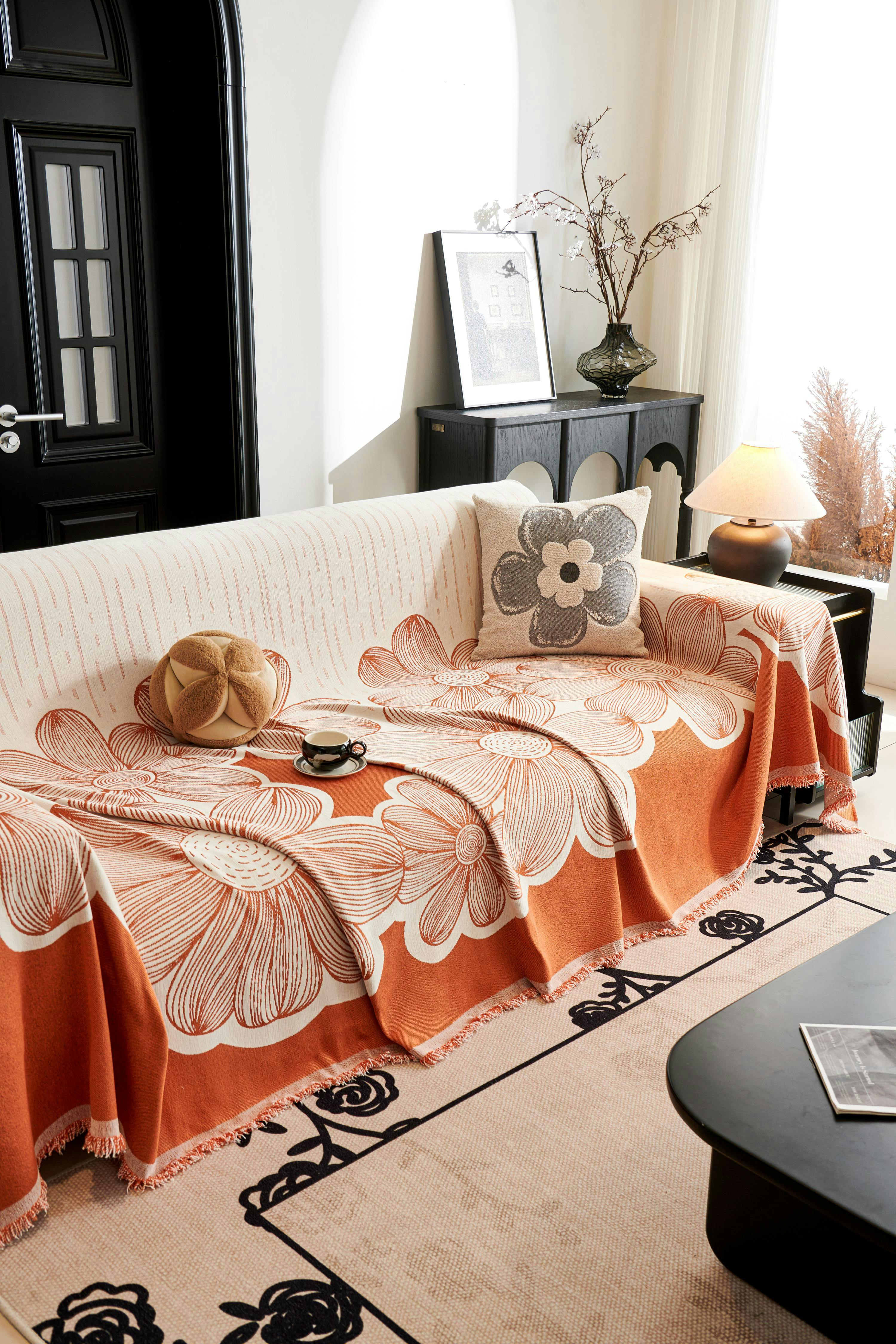 Free A stylish living room featuring an orange floral sofa cover and modern decor. Stock Photo