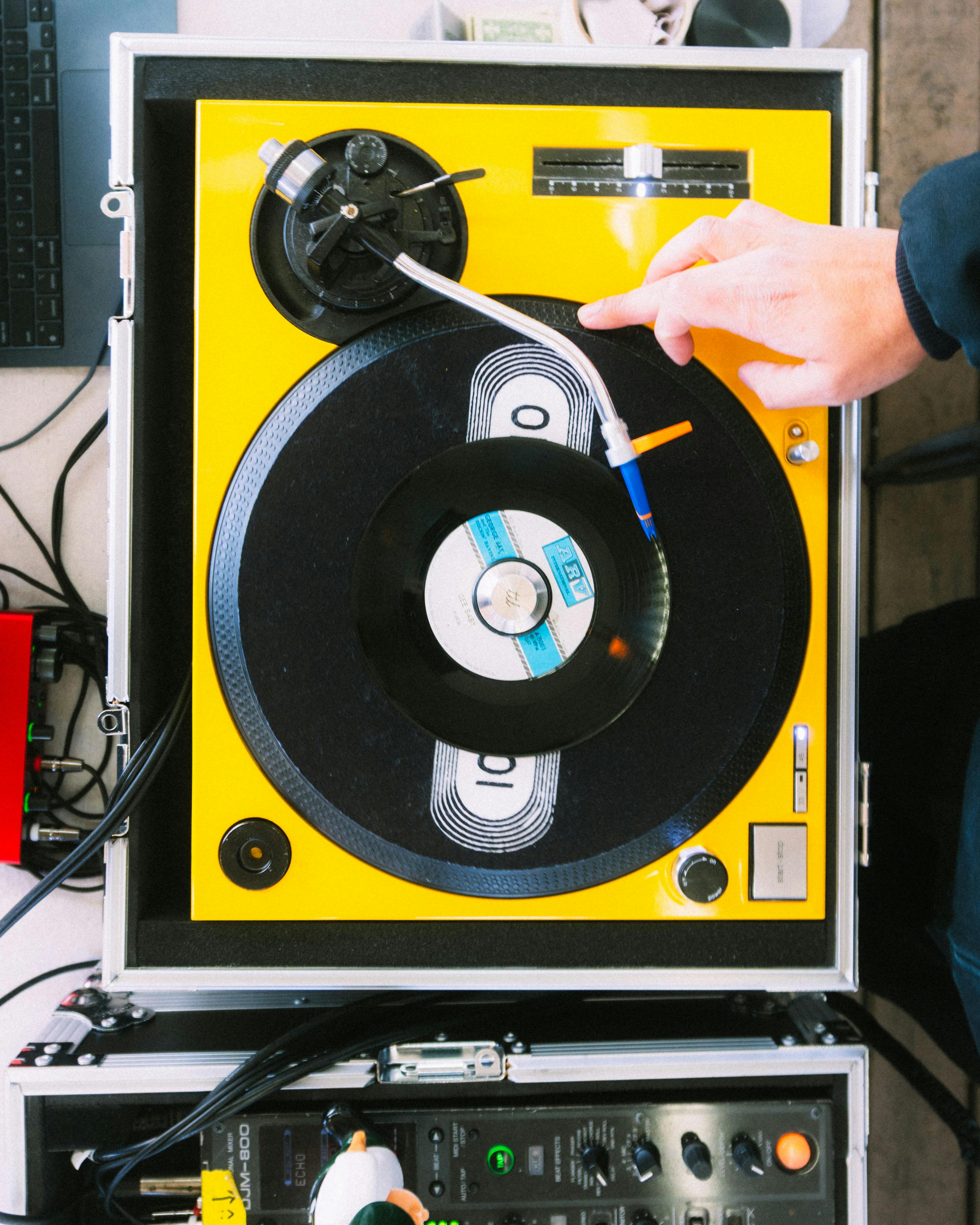 Hand adjusting a vintage turntable with vinyl record, showcasing DJ culture.