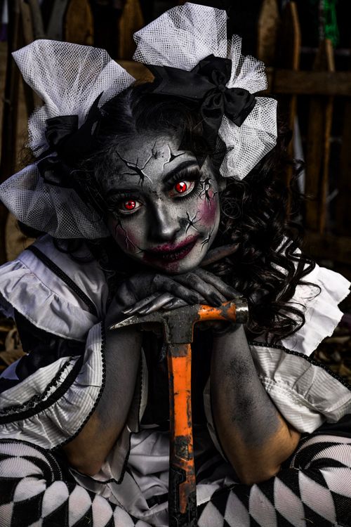Free Creepy clown with cracked face paint and red eyes holding an axe. Stock Photo