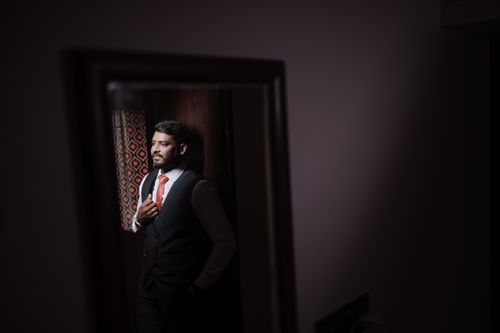 Free A thoughtful groom in a stylish suit and tie, standing indoors, captured in a reflective pose. Stock Photo