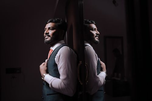 Free An Indian groom in a blue coat reflects introspectively in a mirror. Stock Photo