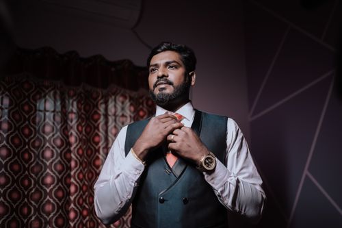 Free Handsome Indian groom adjusting tie in a stylish suit indoors. Perfect for wedding collections. Stock Photo