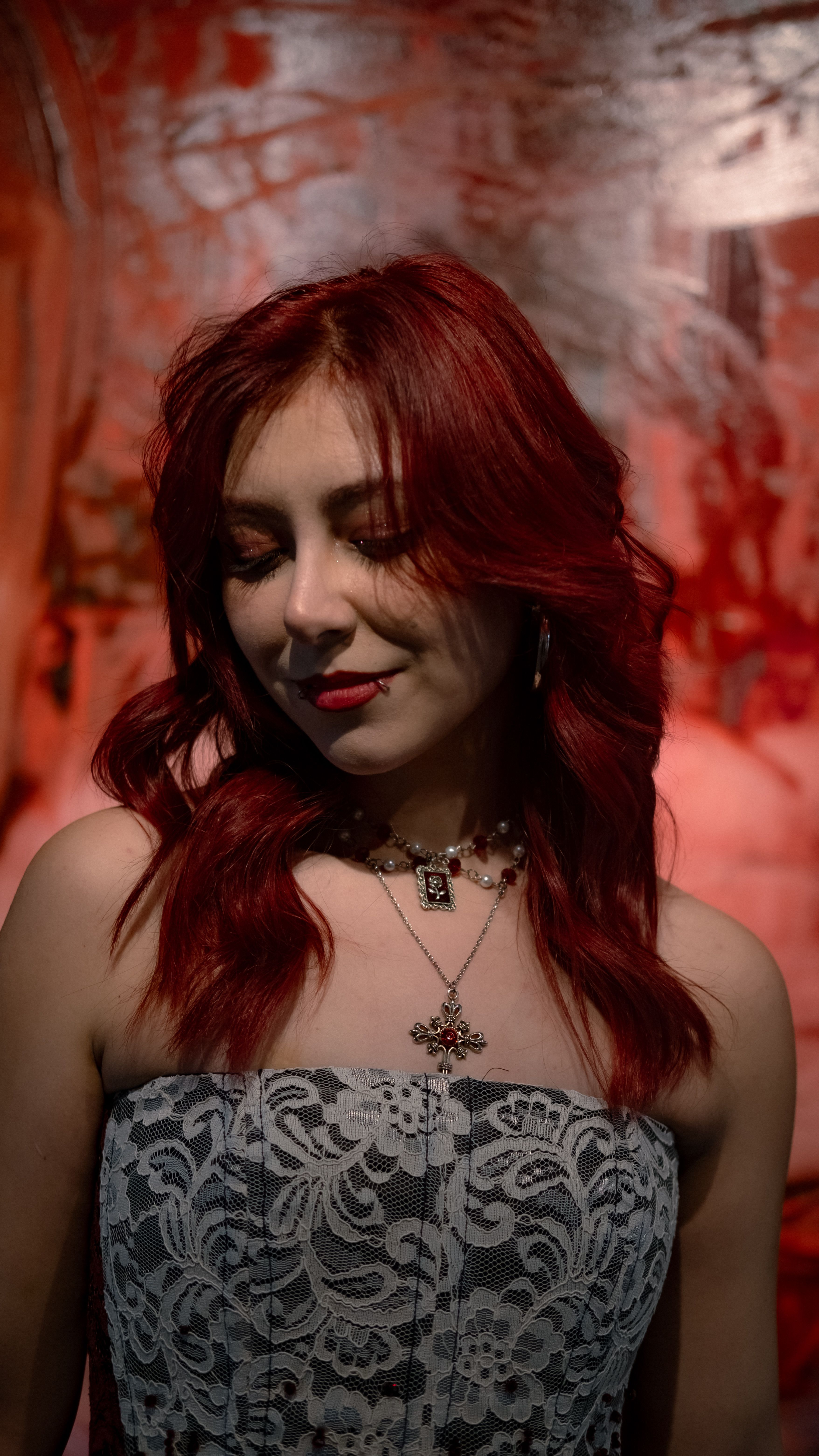 Portrait of a stylish woman with vibrant red hair in an artistic and moody setting.
