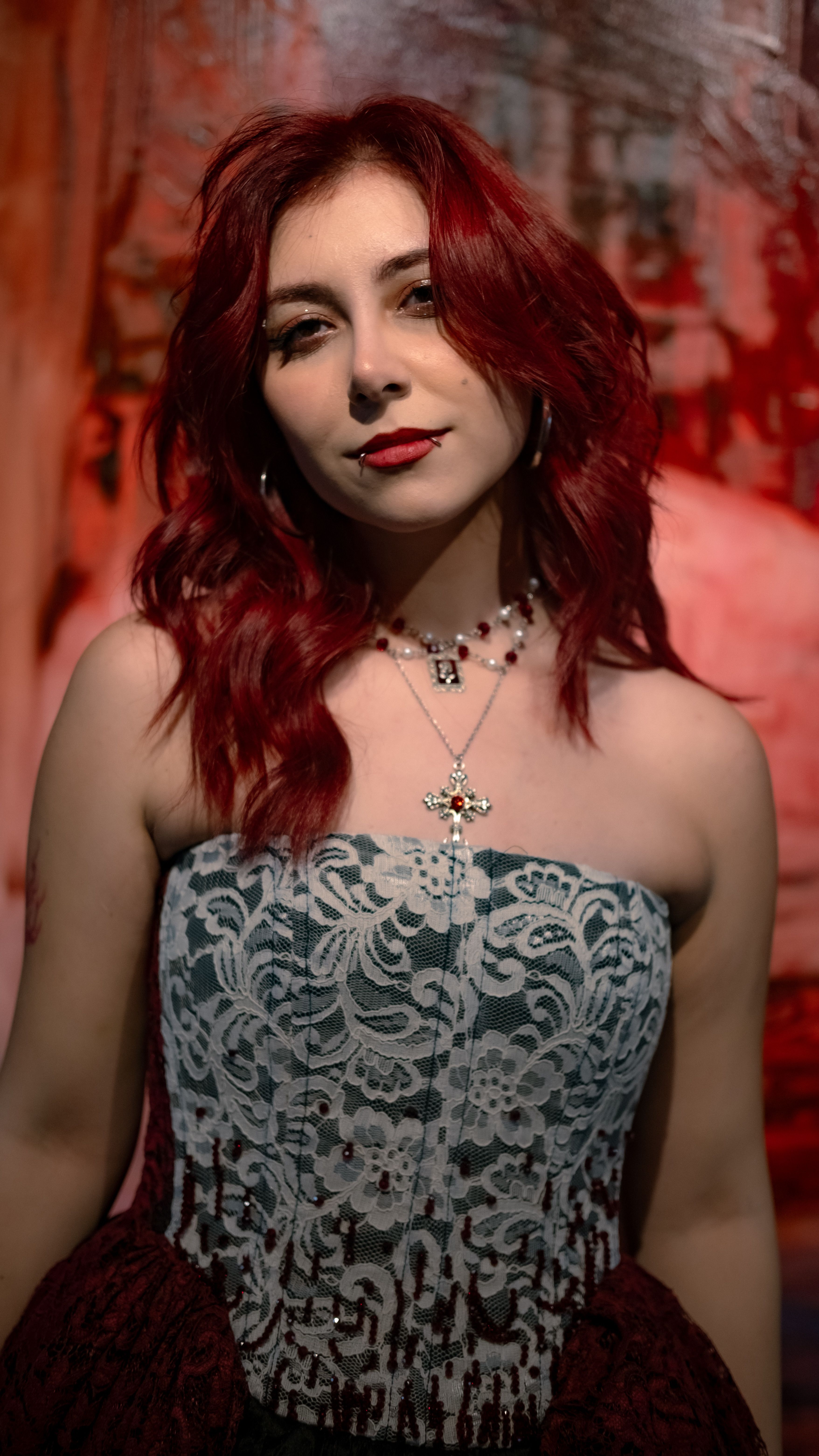 Elegant portrait of a woman with red hair wearing a lace dress and necklace.