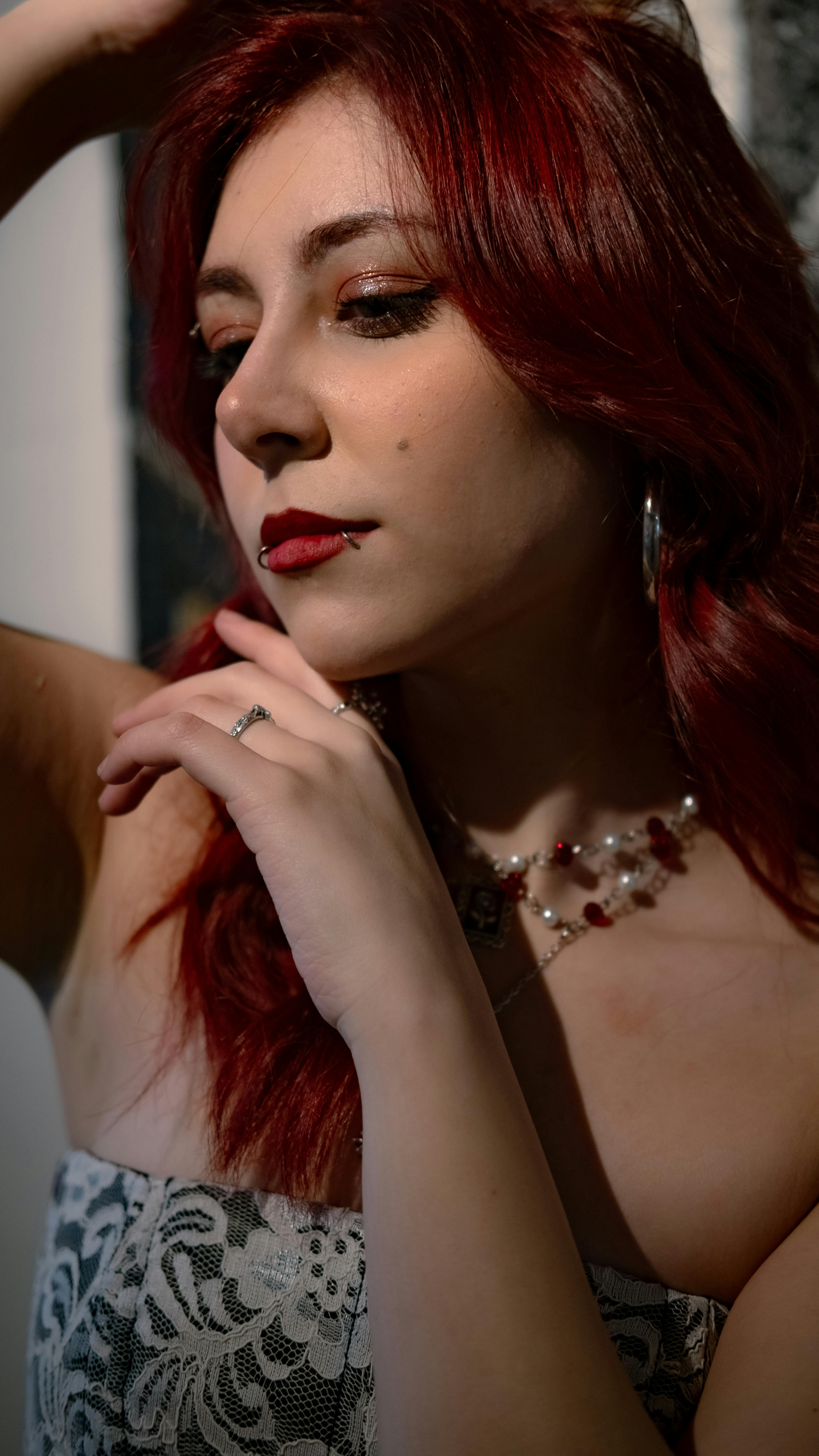 bezplatná Stylová žena s červenými vlasy pózuje v krajkových šatech vyzařujících eleganci a sebevědomí. Ideální pro snímky módních akcií. Základová fotografie