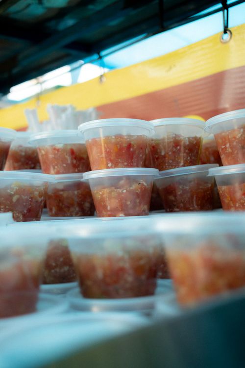 Free Close-up of vibrant salsa containers stacked at a bustling Brazilian street market. Stock Photo