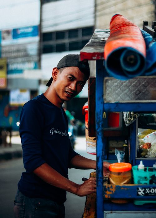 Free A young male street vendor operating a food cart in Jakarta, Indonesia. Stock Photo