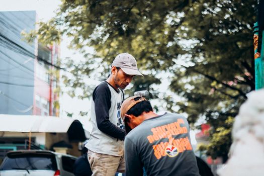 Dynamic street market scene with two vendors interacting in Jakarta, Indonesia.