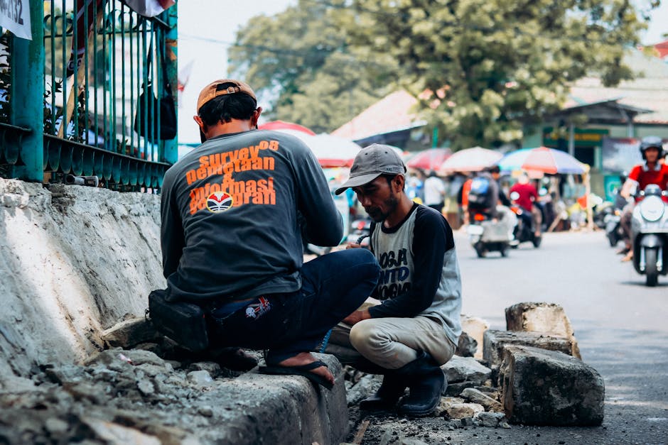 Two men focus on repair work on a busy Jakarta street, showcasing daily urban activities.