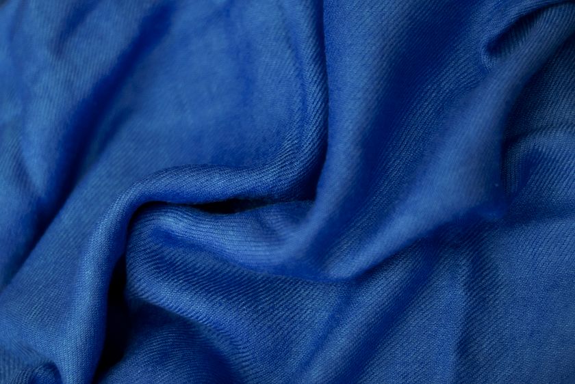 Close-up of a smooth blue cloth in broad soft waves, the light travelling evenly across the folds.