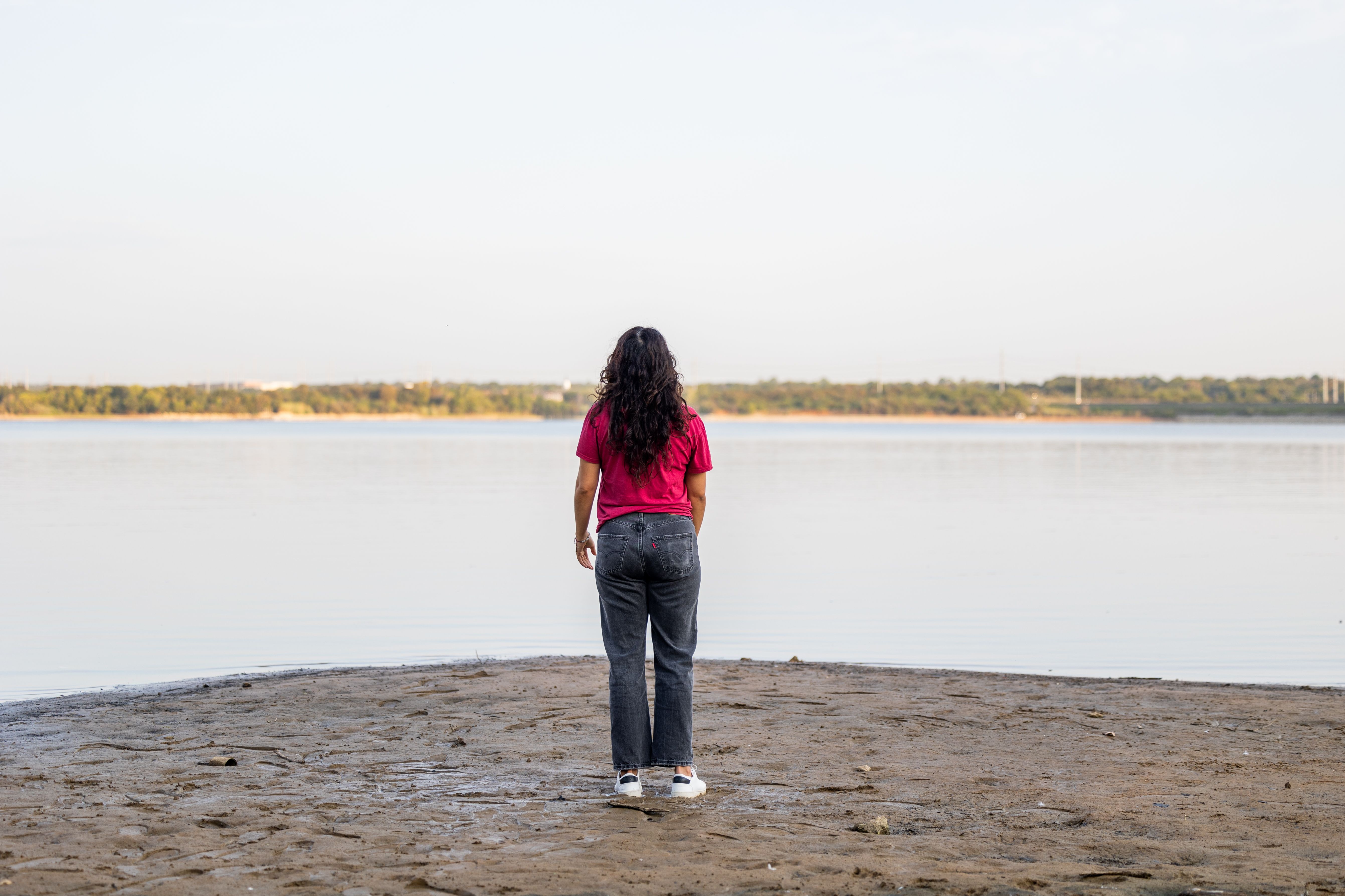 Contemplative Woman Standing by Tranquil Lake · Free Stock Photo