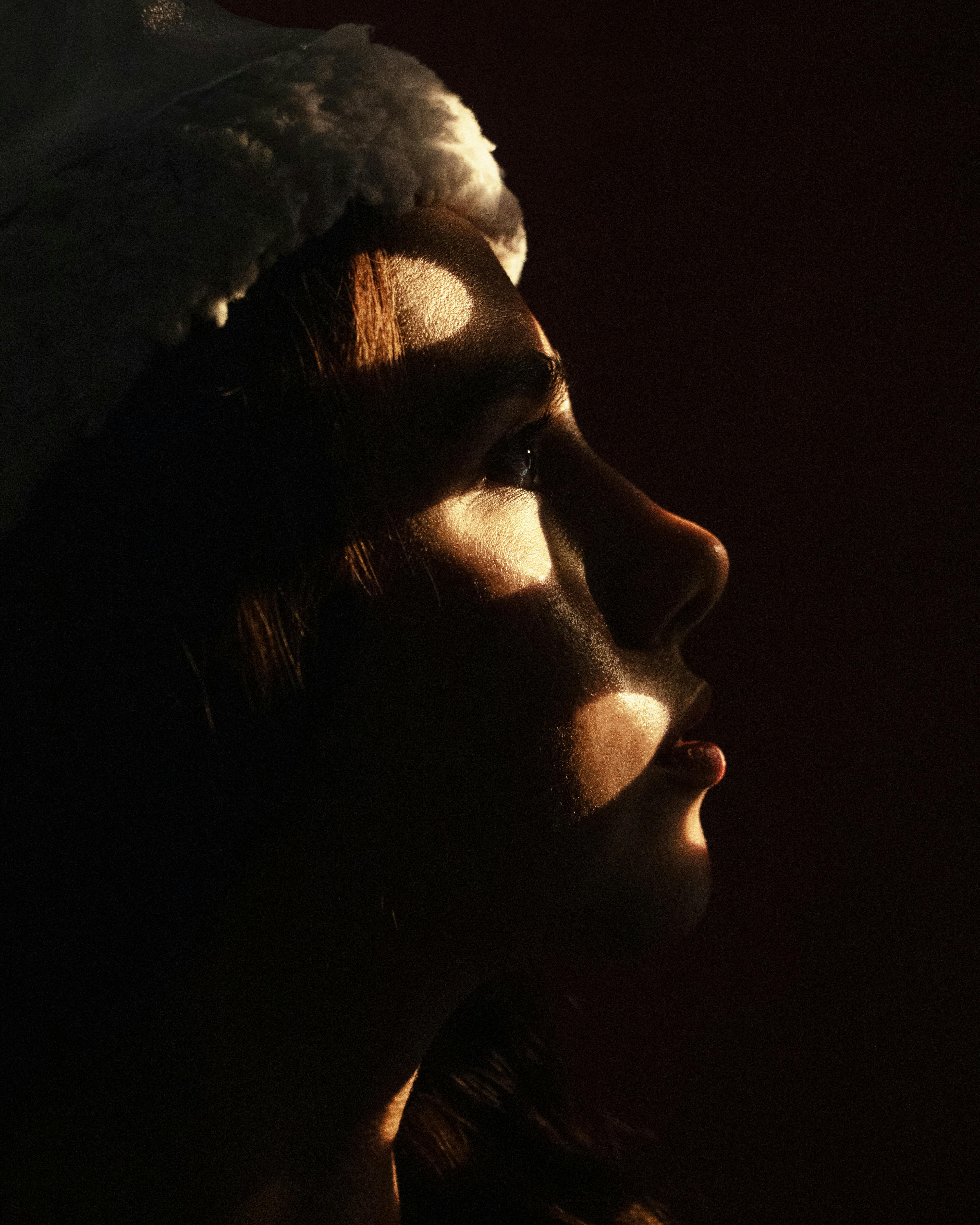 Captivating side profile of a woman with dramatic shadows creating unique patterns on her face.