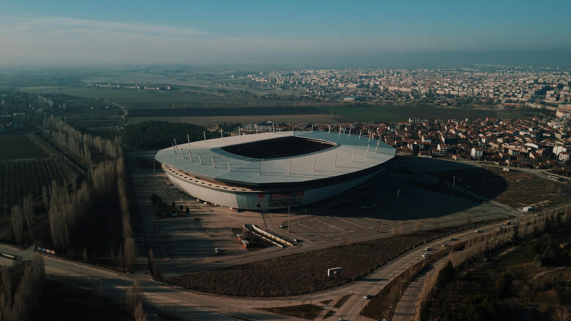 Aerial shot of a large football stadium surrounded by a city and landscape in Turkey.