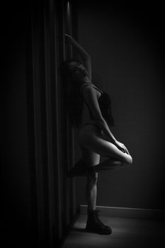 Artistic black and white portrait of a woman in lingerie posing indoors.