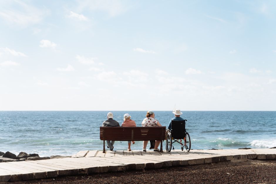 Personas mayores disfrutando de un día tranquilo junto al mar en las Islas Canarias.