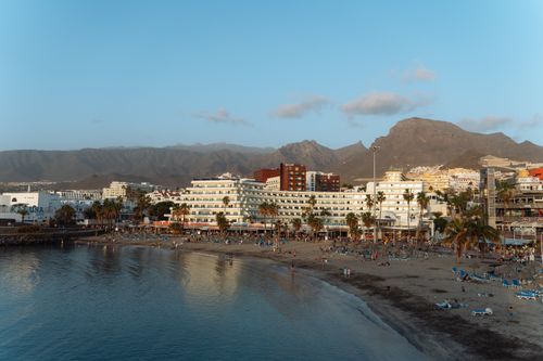 Free Scenic beach in Tenerife, Spain showcasing vibrant urban life and a mountain backdrop. Stock Photo