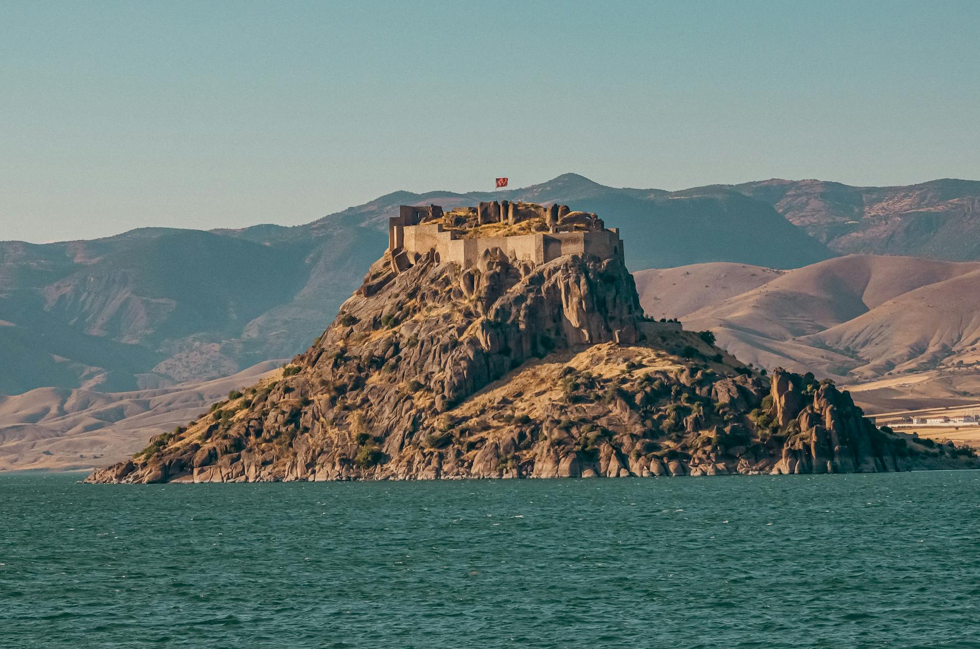 A stunning fortress on an island with mountains and water, showcasing natural beauty and history.