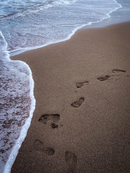 Free Footprints on a serene sandy beach with ocean waves in Canary Islands. Stock Photo