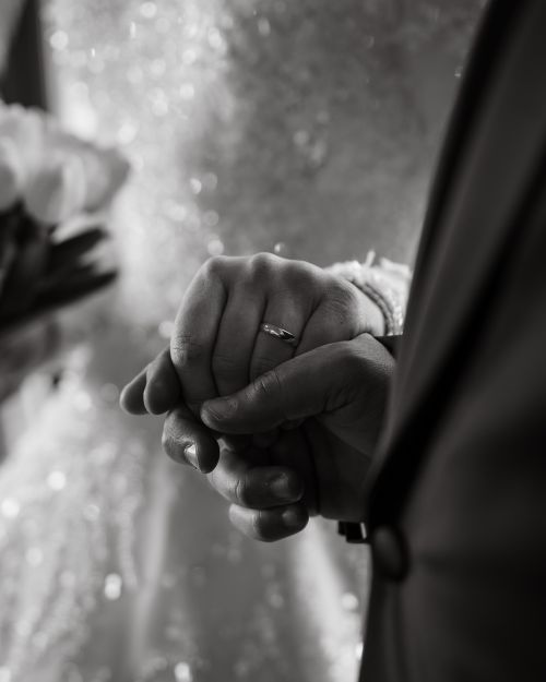 Free A black and white close-up of a wedding couple's hands, symbolizing love and commitment. Stock Photo