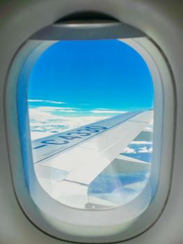 Stunning view of airplane wing and sky through window, clouds visible.