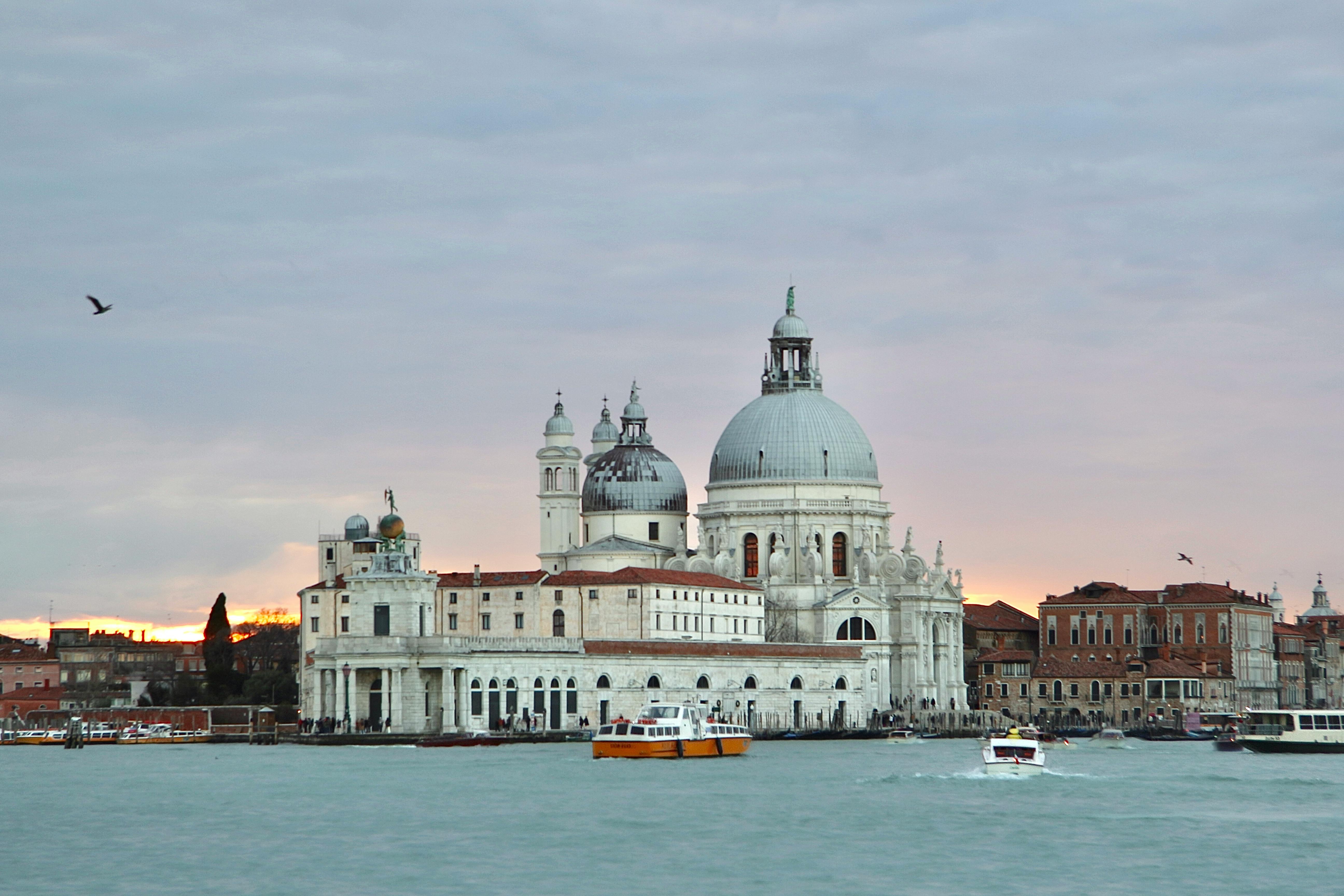 Free View of Santa Maria della Salute with boats on Venice waters at sunset. Stock Photo