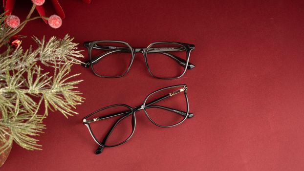 Stylish glasses and festive decor on a red background, highlighting fashion and elegance.