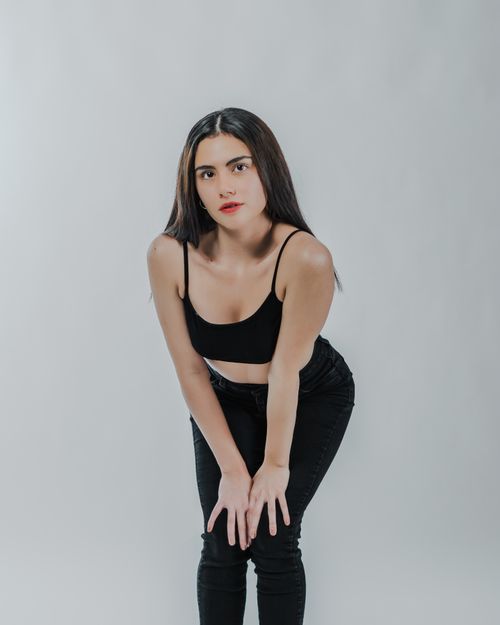 Free A confident young woman poses elegantly in a stylish black outfit against a neutral background. Stock Photo