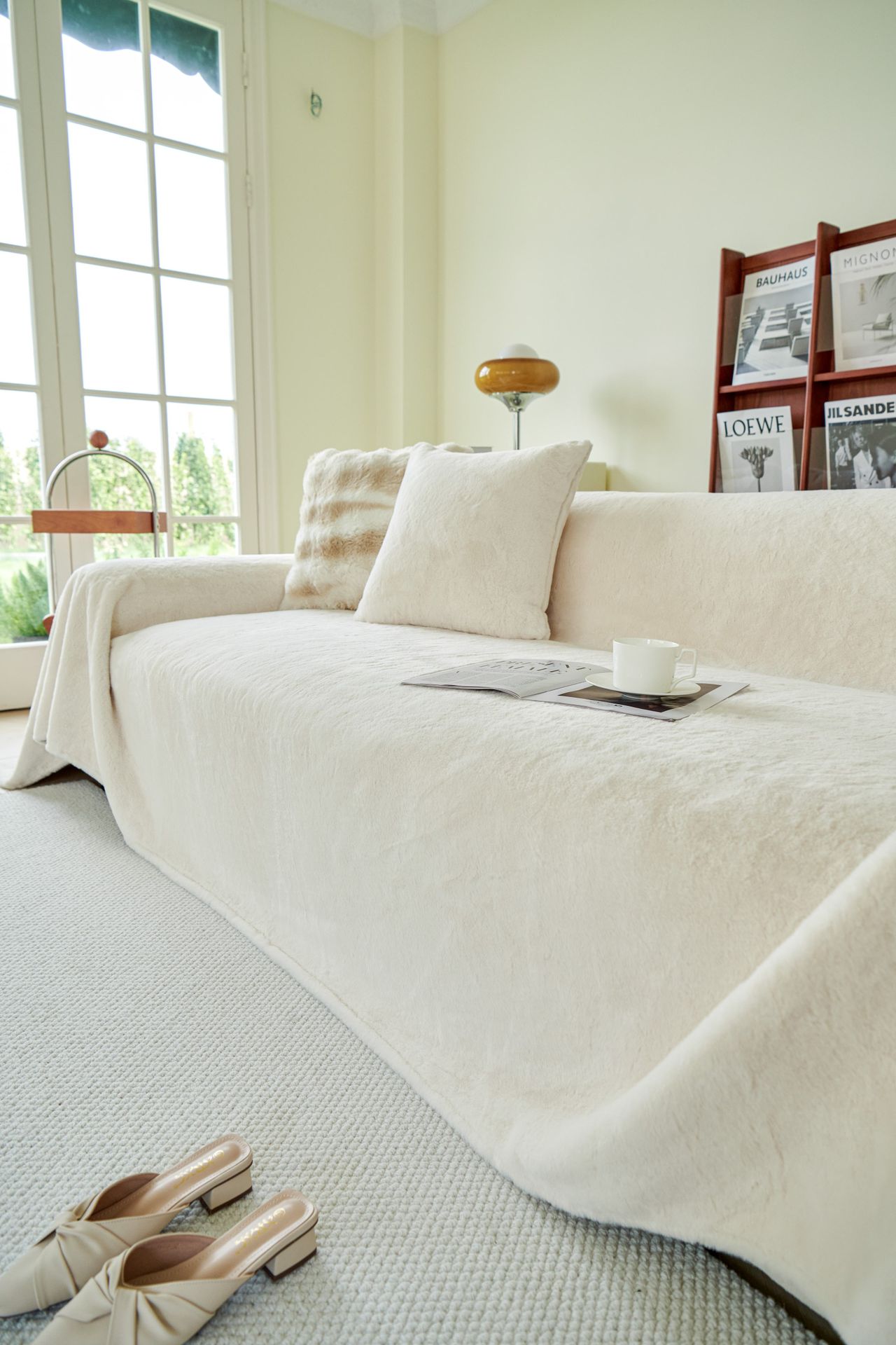 Cream sofa with a cup and magazine resting on a throw