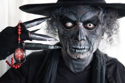 Free Close-up of a person in skeleton makeup and costume, holding beads with claws. Stock Photo