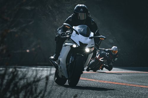 Free Two motorcyclists racing on a curved road, showcasing speed and skill. Stock Photo