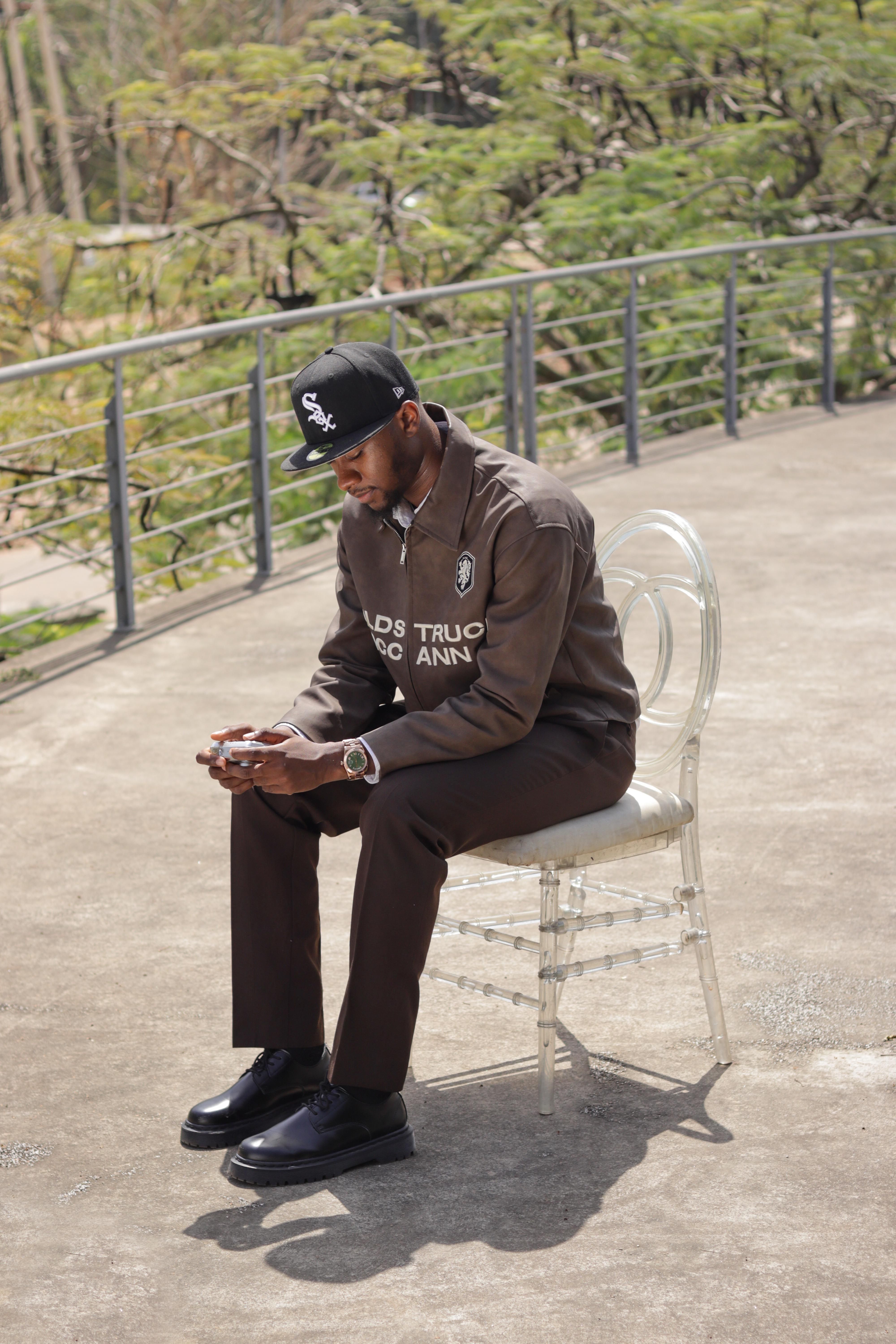 Elegant male model seated outdoors in Abuja, Nigeria, showcasing modern fashion.