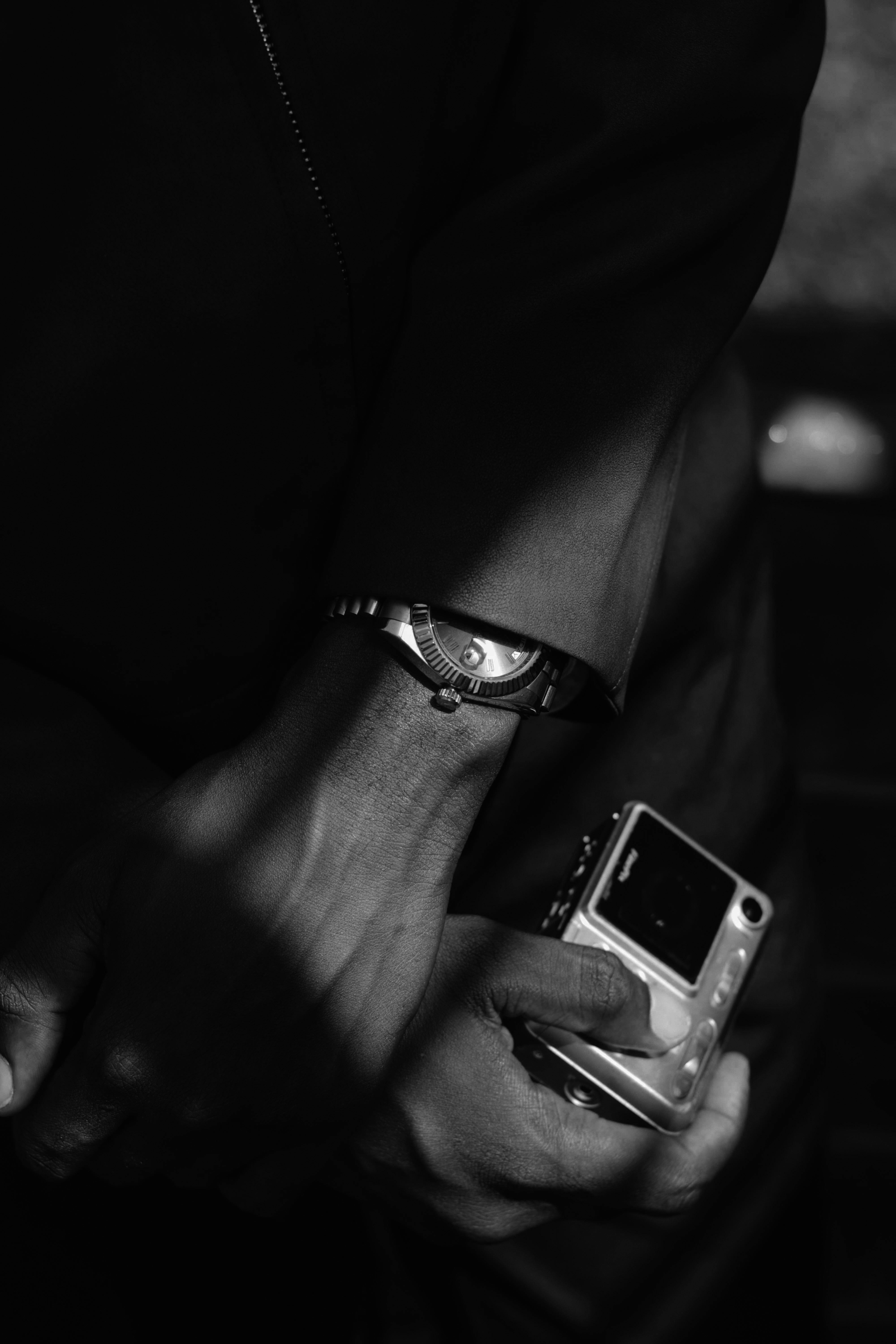 Gratis Elegante immagine in bianco e nero di un orologio da polso e di una macchina fotografica tenuti in mano da una persona. Foto a disposizione