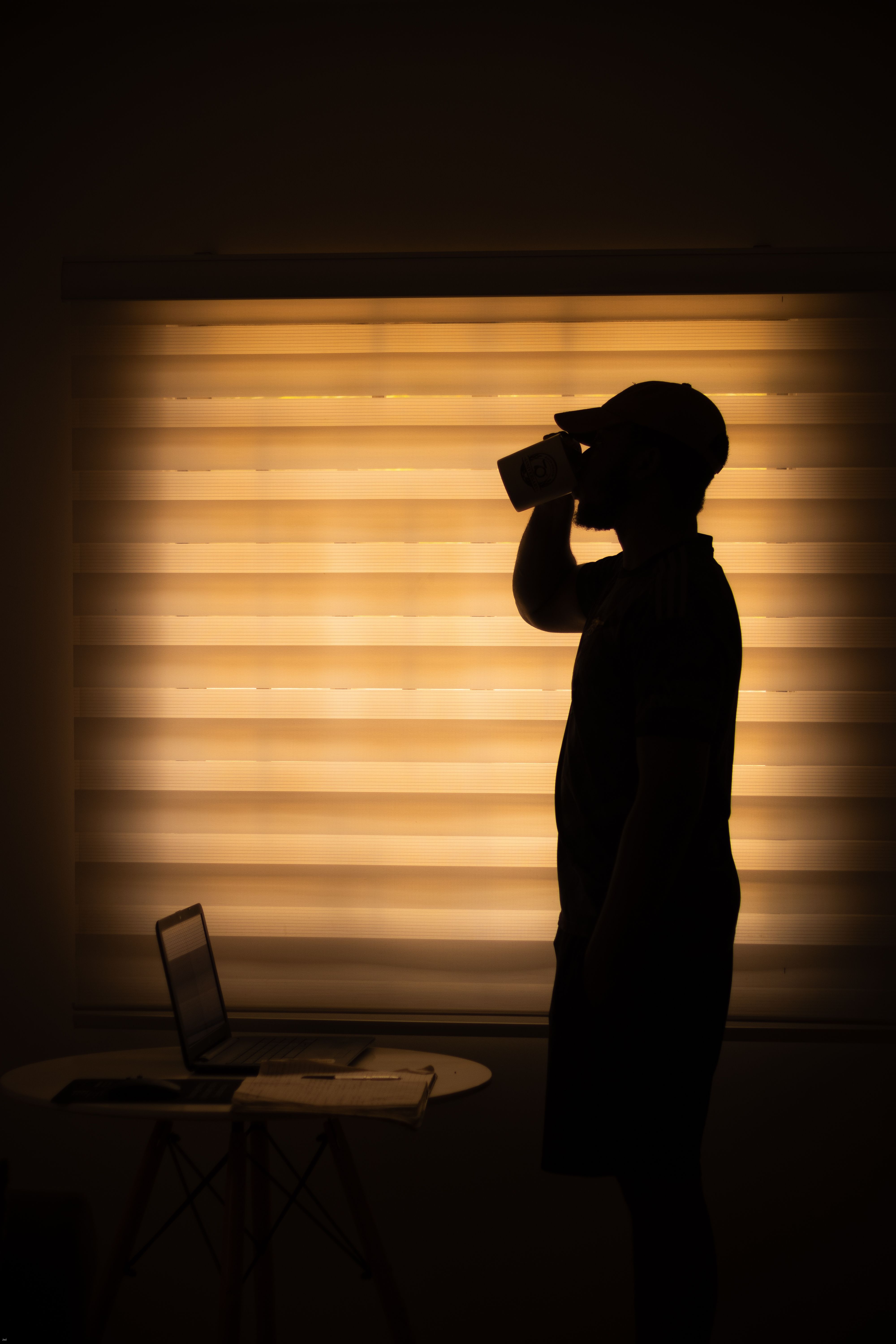 Silhouette of a man sipping coffee while working from home in Abuja, Nigeria.