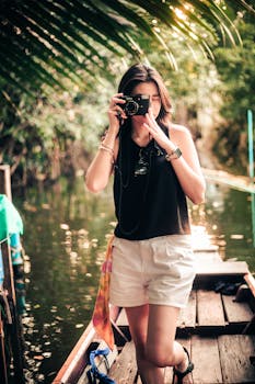 A woman takes a photo while exploring a lush, serene tropical waterway.