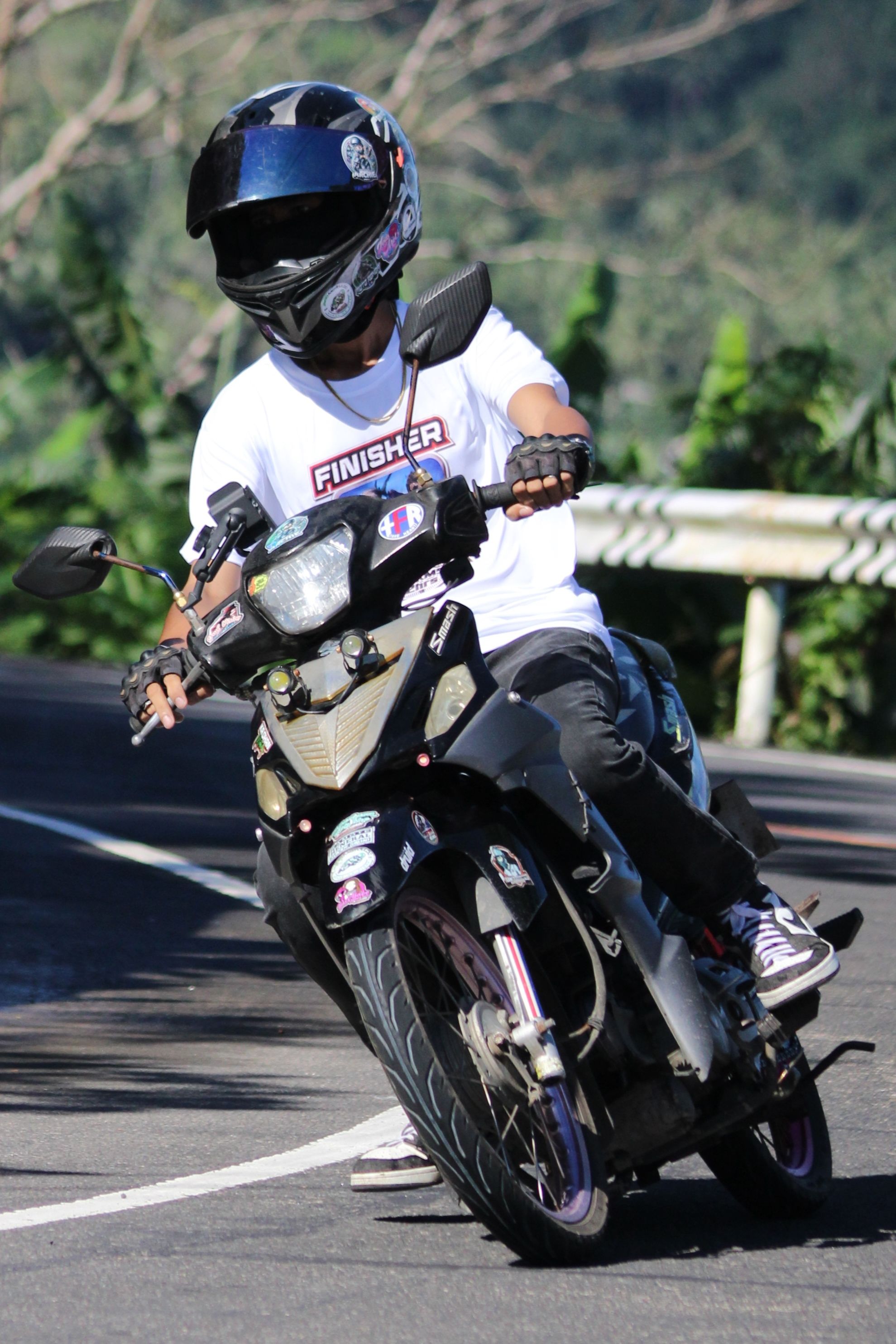 A motorcyclist in gear skillfully navigates a sharp turn on a sunny day.