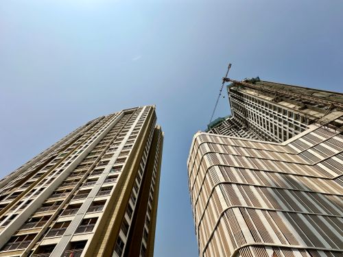 Free Upward view of modern skyscrapers and construction crane in Mumbai against a clear blue sky. Stock Photo