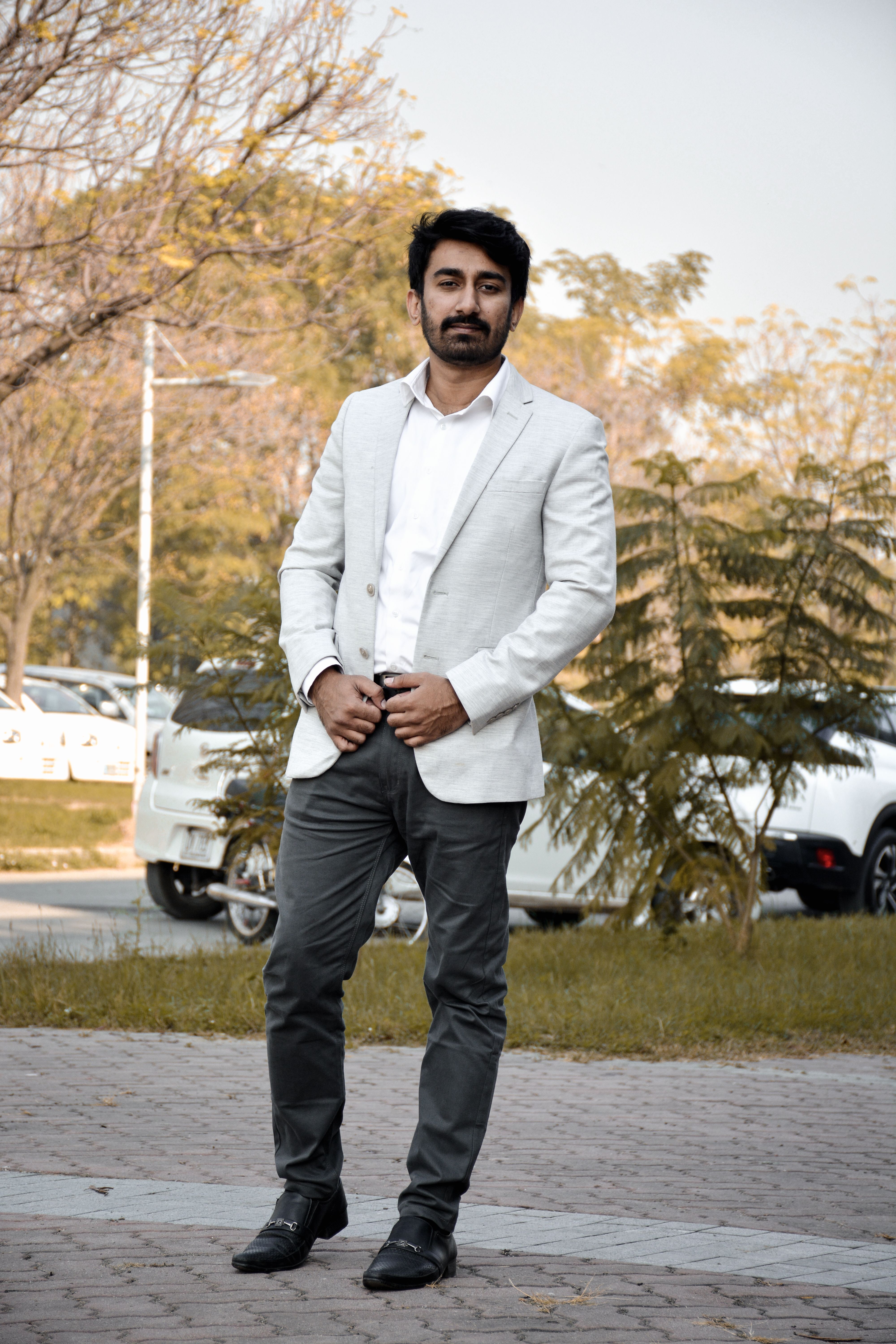 Stylish man in a white suit posing in an outdoor setting in Islamabad, Pakistan.