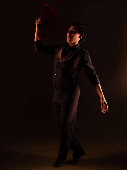 Free Male dancer showcases poise and elegance with a red fan against a dark background. Stock Photo