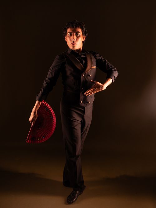 Free An artistic portrait of a male dancer in elegant pose, holding a red fan. Stock Photo