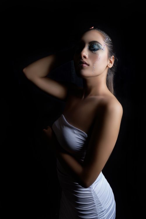 Free Elegant portrait of a woman in white dress with creative makeup and low-key lighting. Stock Photo