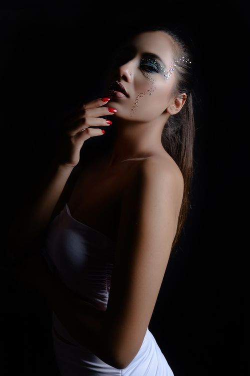 Free Dramatic portrait of a woman with creative makeup in a low light setting. Stock Photo