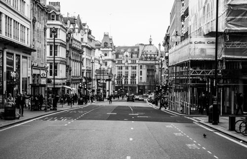 Free Vintage black and white photo of a busy urban street with historic architecture and people walking. Stock Photo