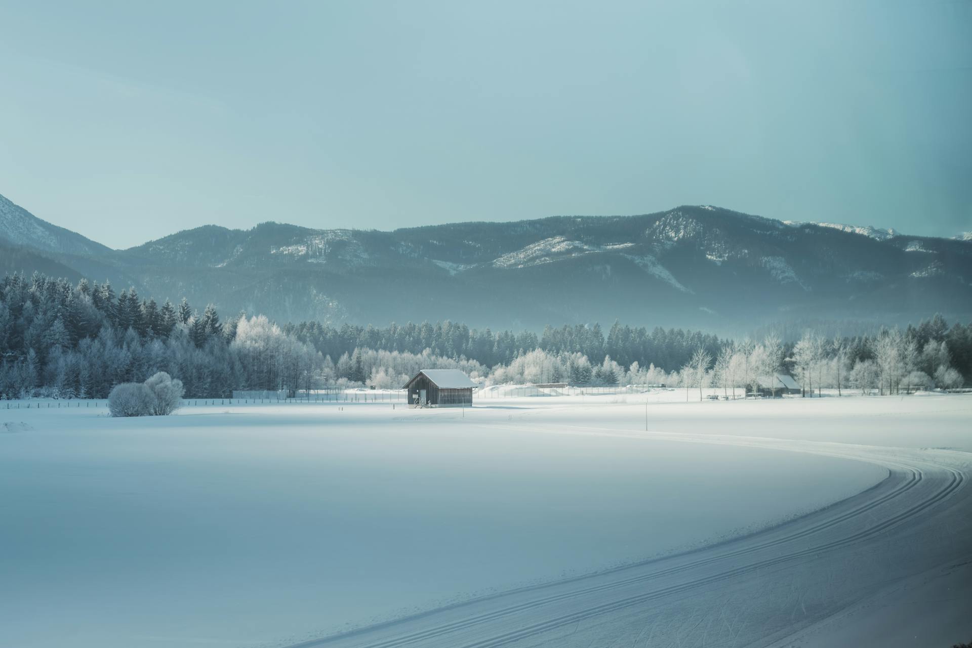 Peaceful winter scene with a snow-covered cabin and mountain backdrop, ideal for calming visuals.